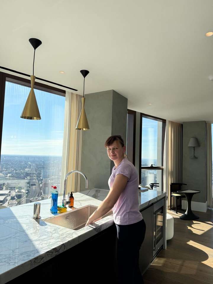 Oksana smiling at the kitchen sink in a London flat