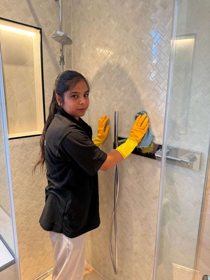 Kamy cleaning a shower in a London home